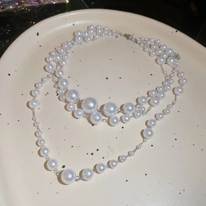 Detail of elegant three-layer pearl necklace with vintage silver metal clasp on a ceramic plate
