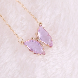 Macro shot of gold necklace with purple gemstone butterfly pendant and small diamonds