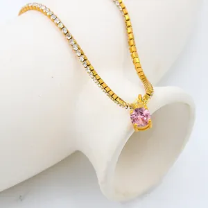 Detail of gold necklace with round pink gemstone and cubic zirconia brick chain