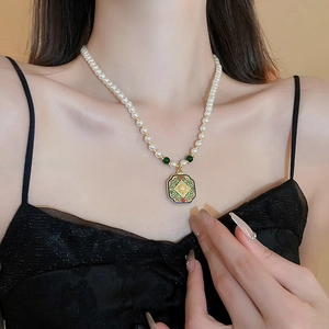 Close-up of a model wearing a vintage emerald enamel lock necklace with pearl strand