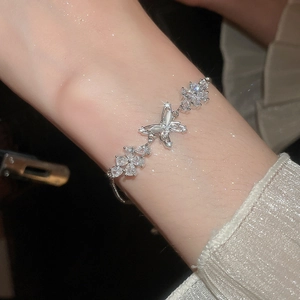 Close-up of butterfly and flower charm bracelet with opal and zircon on woman's wrist