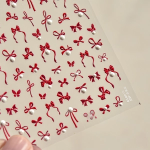 Macro shot of red 3D bow nail stickers with pearls for nail art design decoration