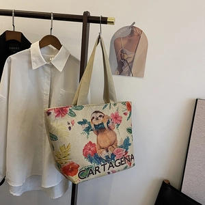 Detailed texture of linen tote bag featuring a sloth and floral print hanging on a hanger