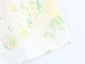 Close-up of floral embroidery and printing on white fabric with detailed needlework