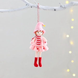 Cute Christmas doll ornament in pink dress and red boots hanging on a tree branch