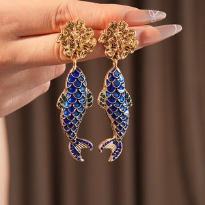 Detailed shot of vintage gold fish earrings with blue enamel and sparkling rhinestones