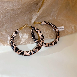 Close-up of large gold hoops with dark leopard print texture and high-fashion finish