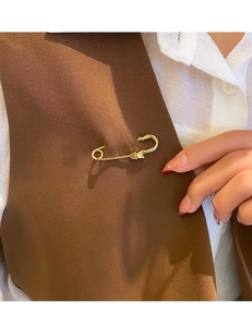Close-up of a golden safety pin brooch being styled on a brown vest for waist adjustment