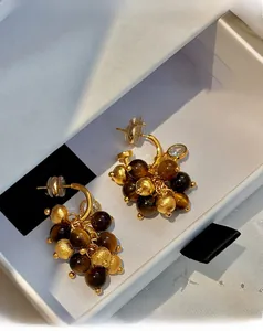 Detail of cluster drop earrings with tiger eye beads and zircon stones in a white box