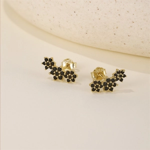 Macro detail of gold S925 silver stud earrings with black zircon floral design