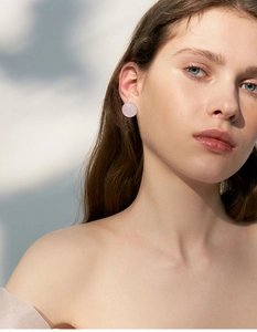 Close-up of a pink round resin earring worn by a model for a luxury aesthetic look