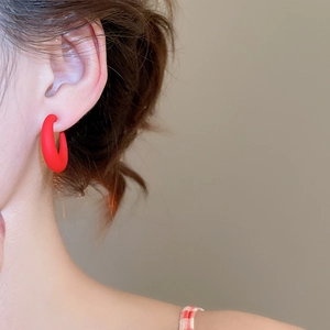 Macro side view of a woman wearing minimalist matte burgundy C-shaped acrylic hoop earrings