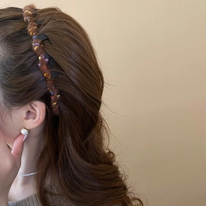 Detail of a brown knitted wool headband on a model with pearl earrings and necklace