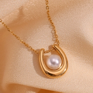 Detailed close-up of 18K gold-plated U-shaped horseshoe pendant with white pearl