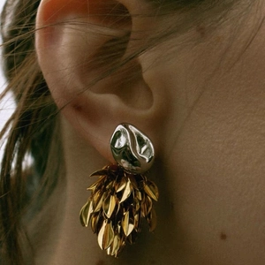 Macro view of bicolor leaf tassel earrings with polished silver and gold elements