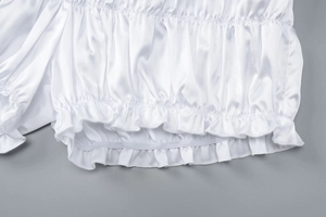Detailed macro view of white satin fabric showing ruffled edge and elastic pleated textures