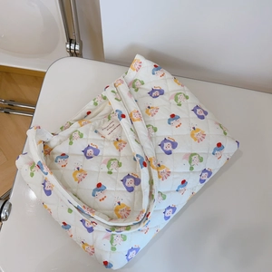 Detail of floral quilted tote bag featuring colorful cartoon prints and inner woven label