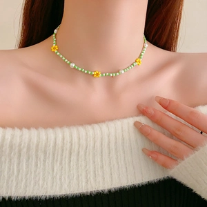 Detail of beaded flower necklace with green, white beads and pearls on model neck