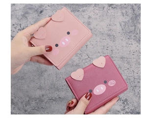 Close-up of cute pig-shaped wallets in pink and rose red PU leather with heart detail