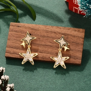 Detail of gold-plated star earrings with pavé crystals on a festive wooden surface