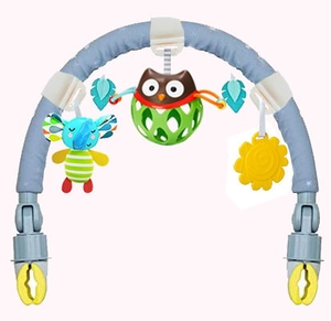 Detail of baby stroller activity arch featuring a plush elephant, owl rattle, and sun teether