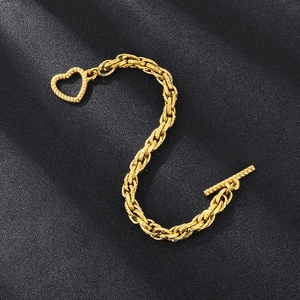 Macro detail of golden stainless steel curb chain bracelet with heart-shaped toggle clasp