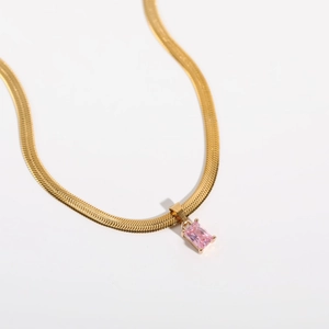 Detail view of a 18K gold plated snake chain necklace with pink zircon pendant