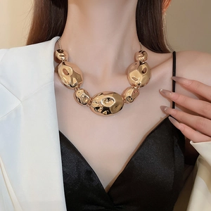 Close-up of gold chunky irregular beaded necklace showing polished metallic texture and shine