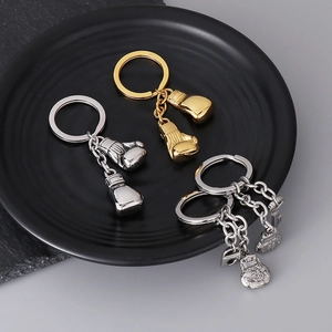 Polished gold and silver boxing glove and lucky bag pendants on a black tray