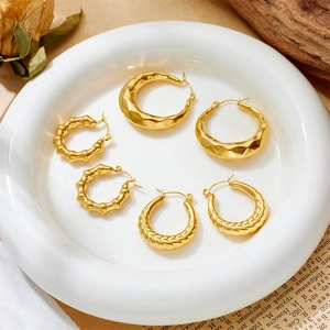 Three pairs of gold stainless steel textured hoop earrings on a vintage background