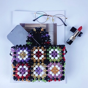 Flat lay of colorful beaded handbag with geometric patterns and everyday accessories