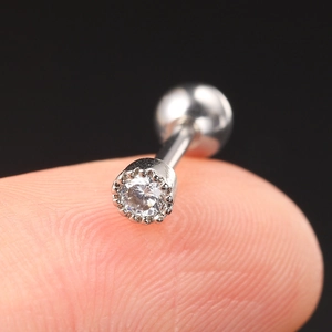 Macro shot of silver stainless steel cartilage stud with round zircon held on a fingertip