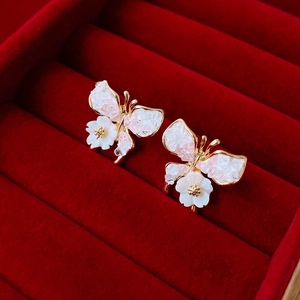 Detail of butterfly earrings with pink crystal stones and white flower in a velvet box