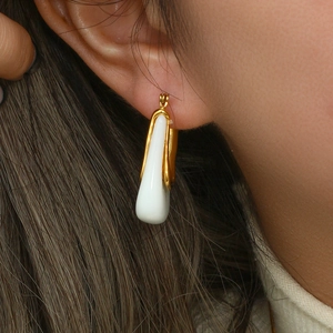 Detailed close-up of C-shaped drop earrings with white inlay and gold metallic frame