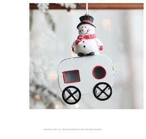 Close-up of a snowman ornament in a red camper van hanging on a Christmas tree
