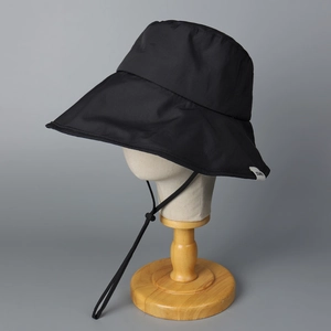 Détail d'un chapeau de soleil noir à large bord avec cordon réglable et étiquette latérale