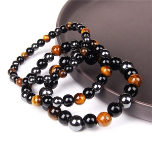 Three-piece set of tiger eye, obsidian and hematite beaded bracelets on a ceramic plate