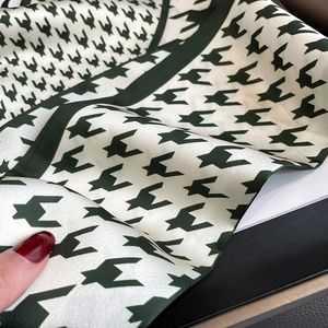 Detail shot of green houndstooth satin scarf with luxurious smooth texture and geometric print