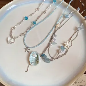 Starfish and seashell charm necklaces with blue beads in a gift tray for summer beach style