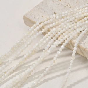 Detailed view of 3mm natural white freshwater shell round beads on a stone for DIY jewelry