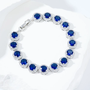 Macro detail of silver-tone tennis bracelet with round deep blue stones and zircons
