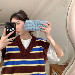 Close-up of a light blue bubble fabric pouch being held in a mirror selfie