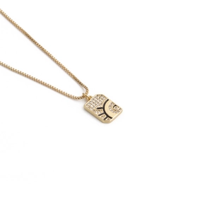 Detail view of a gold evil eye pendant with cubic zirconia and black enamel on box chain