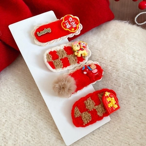 Détail de barrettes festives en peluche rouge avec breloques Lucky et vœux de Nouvel An