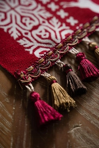 Close-up of Christmas table runner jacquard fabric with elegant red and gold tassels