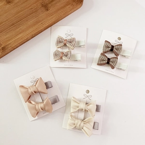 Detail of four pairs of sweet fabric bow hair clips in satin and plaid textures on a card