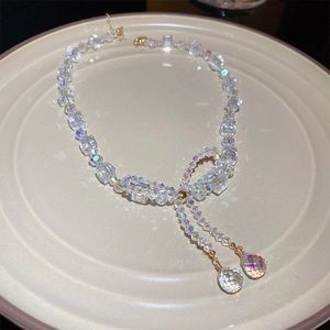 Close-up of elegant crystal beaded bow necklace with golden water drop pendants