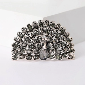 Macro shot of silver-tone peacock brooch featuring sparkling grey rhinestones and metalwork