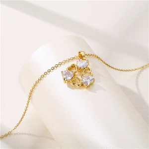 Collier en acier inoxydable doré avec quatre pendentifs cœur en zircon sur fond blanc