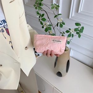 Pink jacquard mini makeup bag with embroidered floral texture and branded woven label